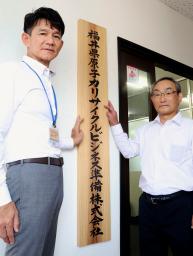 福井県原子力リサイクルビジネス準備株式会社の事務所入り口に看板を設置する来馬克美社長(右)ら=1日午前、福井県敦賀市