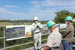 中間貯蔵施設を巡るバスツアーの参加者に説明する施設の職員(奥)=9日午後、福島県大熊町