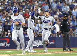 ワールドシリーズ第1戦の7回、2ランを放ち三塁コーチとタッチを交わすドジャース・大谷(右)=24日、トロント