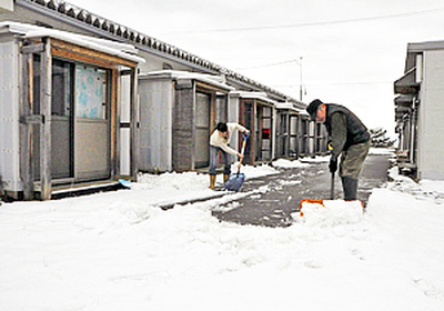 仮設住宅の除雪を行う住民。入居者が減ってひっそりとしている＝会津若松市・松長近隣公園仮設住宅