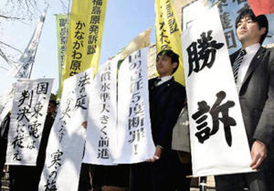 判決を受け、横浜地裁前で旗を掲げる弁護士ら