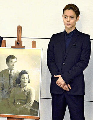 古関夫婦の写真とともに、記念撮影に応じた窪田さん＝７月２３日、福島市役所