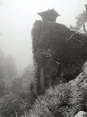 突き出した岩壁の上に立つ納経堂。降りしきる雪が異界に迷い込んだような浮遊感をかき立てる＝宝珠山立石寺