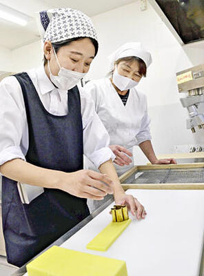 須田さん（右）の指導を受けながら、黄色のようかんをイチョウ形に型抜きする記者
