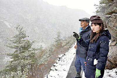 源泉近くの山道で武田さん（左）から説明を聞く記者。文字通りの断崖絶壁だ