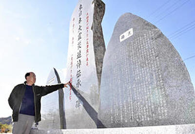 「ここで起きた出来事を後世に伝えたい」と石碑に手を添える木田さん＝いわき市