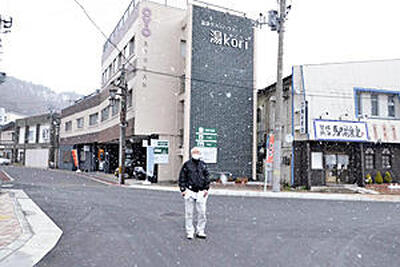 映画のスチール写真で森繁久弥が立っていた辺りを推定して立つ上野芳郎さん＝磐梯熱海駅前
