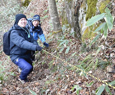 花塚山の頂上を目指す記者（左）。場所によっては補助ロープを頼って登る急斜面もある