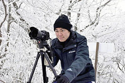 富士山撮影に挑む記者。富士山遠望隊のメンバーから借りた三脚を使い、富士山が写ることだけを願って神経を集中させる