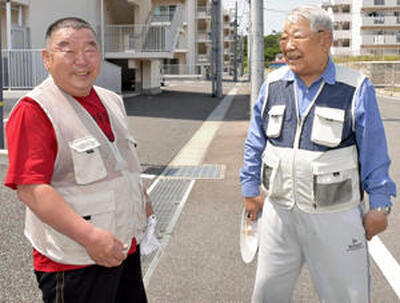 遠藤さん（左）と藁谷さんはかつて互いを分断していた道路を前に笑顔で語り合う＝いわき市小名浜