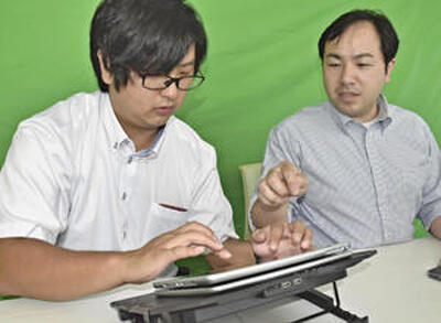 小林さん（右）から「伝説対決」の操作方法を教わる記者。最初はゲームの仲間や対戦相手が見つからず苦労した