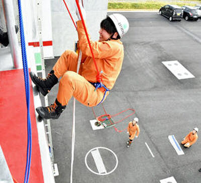 引き揚げ救助訓練で、顔をゆがませながら訓練塔を登る記者。地上７メートルの高さを登り降りする訓練はバランスを取るのがとても難しい