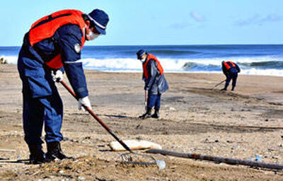 新地町の海岸で砂をかき分けて行方不明者の捜索に当たる相馬署員＝２０２２年１月１９日