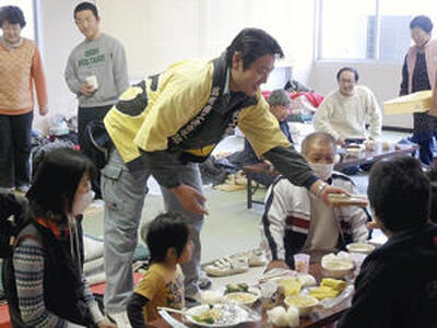 塙町で炊き出しを手伝い、避難者に焼きそばを手渡す八島氏。これが震災後に「浪江焼麺太国」が活動を再開させるきっかけとなった＝２０１１年３月