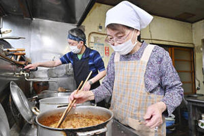 鶏皮をじっくりと煮込むいく子さん（右）。和久さんと協力して店の味をつないでいる（石井裕貴撮影）
