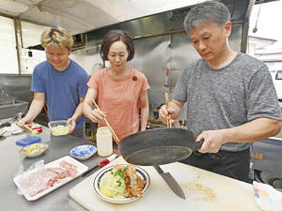 台所で料理を盛り付ける（右から）店主の小宅直美さん、妻三智子さん、長男功貴さん。家族３人で店を切り盛りする（永山能久撮影）
