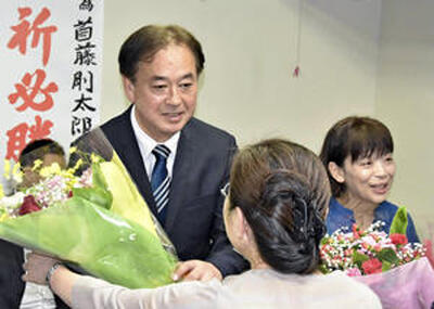 初当選し、支持者から花束を受ける首藤氏（左）と妻亜希子さん