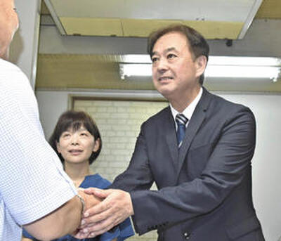 初当選し、支持者と握手を交わす首藤氏（右）と妻亜希子さん＝３０日午後９時半ごろ、石川町