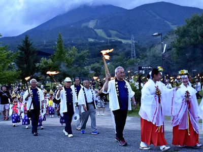 磐梯山を背景に「たいまつ行列」を行う参加者