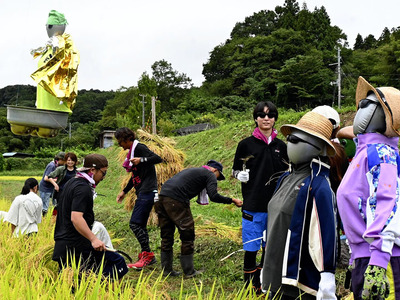 宇宙人のマスコットに見守られながら稲刈りをした地域住民ら＝福島市飯野町