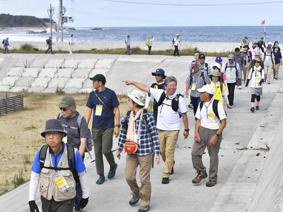 海沿いの風景を見ながら防波堤を歩く参加者＝浪江町・請戸漁港付近