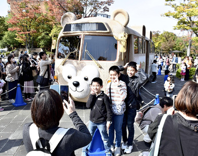 ダッフィーバスの前で記念撮影をする市民ら