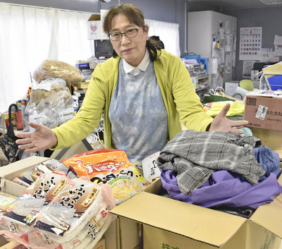 事務所に届く食料品、衣類と私。頂いた品には、寄付してくれた人たちの役立ててほしいとの思いが詰まっている