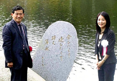 愛をテーマにした俳句が刻まれた御影石を挟み記念写真に納まる私（左）と黛さん。ちょっとした発想の転換で、村に自慢の名所を生み出すことができた