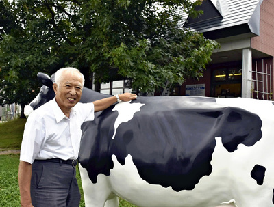 牛のオブジェが出迎える工場脇の直売所「アイス工場」の前に立つ私。会津に生かされていることを忘れることなく、これからもおいしい乳製品作りに励みたい