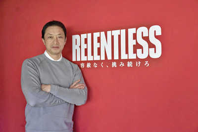 新スローガン「ＲＥＬＥＮＴＬＥＳＳ（リレントレス）　容赦なく、挑み続けろ」の題字の前に立つ私。いわきＦＣが戦うカテゴリーは変わっても、挑戦し続ける姿勢は変わらない
