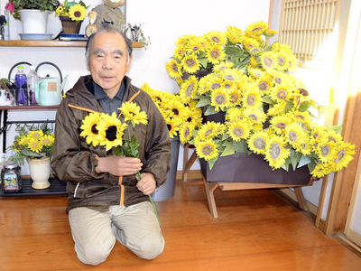 ヒマワリの造花を手にする私。ヒマワリは万国共通の親しみやすさがあり、地域おこしで交流するには、うってつけの花だ