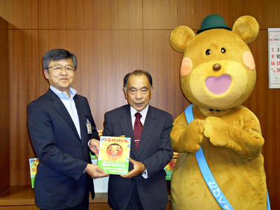 県立図書館に本「ぼくのひまわりおじさん」を寄贈する私（中央）。震災の教訓を知るために手に取ってページをめくってもらえると幸いだ