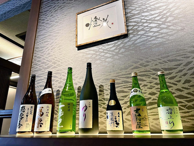 吉川屋の食事会場の入り口に並ぶ日本酒の瓶。本県の日本酒のおいしさを宿泊者の方々にもお知らせしたい
