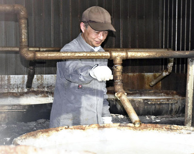 大鍋で温泉水を煮込み、会津山塩を製造する私。長い歴史を持つ山塩作りに携わり、背筋が伸びる思いだ