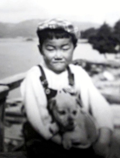 桧原湖を背景に愛犬と一緒に写る幼少期の私。両親は仕事で忙しかったため、祖母と過ごすことが多かった