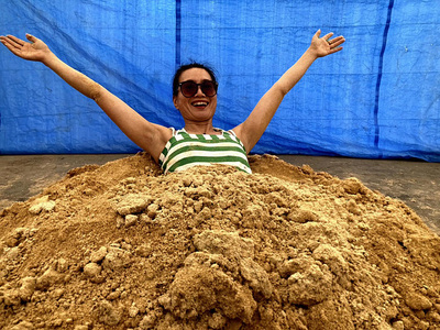 こだわりの有機肥料の中でリラックスする私。お客さんに入って楽しんでもらうこともある。肥料の中は温かく、ビニールハウス内にいい香りが広がる