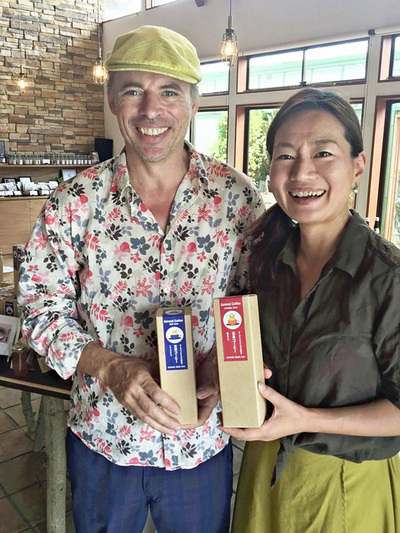 フクシマートの店頭に立つ私と夫のリチャード（左）。手にするのは開発した「玄米コーヒー」。農家仲間と切磋琢磨（せっさたくま）したり、商品の魅力をお客さんに説明できたりする画期的な場所だった
