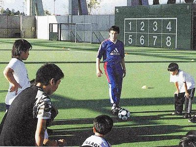 サッカースクールで子どもたちを指導する私（中央）。基礎から徹底して教え込んだ（電気新聞提供）