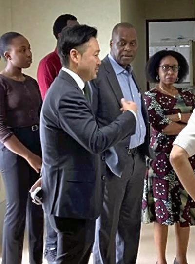 ルワンダのアーネスト・ルワムキョ駐日大使（手前左から２人目）にクリーンルームでの野菜の栽培方法などを説明する私（手前左）。ルワンダでの工場建設に向けて、昨年７月に喜多方市の工場を視察してくれた