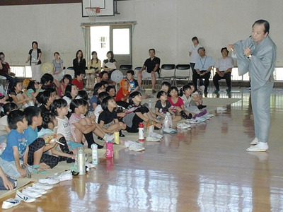 日本大震災後に郡山市の小学校を訪問した時の私（右）。最初は傷ついた被災者に「笑おう」と呼びかけていいものか迷いました。慈善オークションの売り上げや落語会の出演料などを地元に寄せました＝２０１１年７月