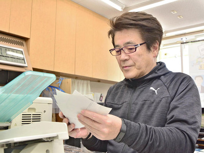 印刷した写真を手にする西村さん。「写真は人に力を与えてくれる」と話す