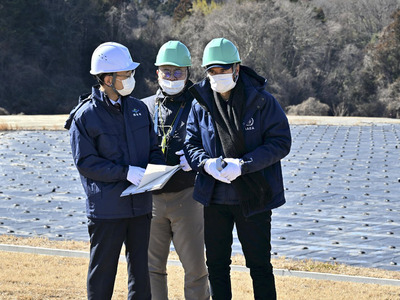 環境省から説明を受けるグロッシ事務局長（右）。背後には大量の除染土壌が埋められている＝２月１９日、中間貯蔵施設
