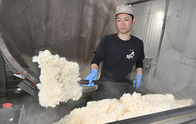 蒸したコメを放冷機に入れる蔵人＝喜多方市・飯豊蔵