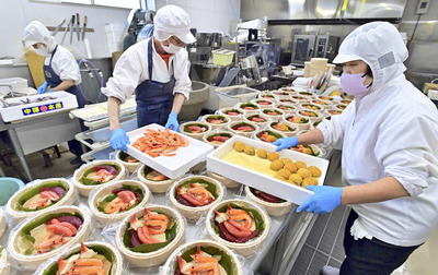 作業台に並べたたるに食材を詰め込む従業員。刺し身の盛り合わせをイメージした盛り方にしている