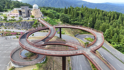 神秘的な世界を体験できる「あぶくま洞」と、「星の村天文台」（左奥）とをつなぐ歩道橋「天地人橋」。円形の橋の下から見上げると、輪の中に星空が広がり、人気の観光スポットとなっている＝田村市滝根町・あぶくま洞（ドローン撮影）