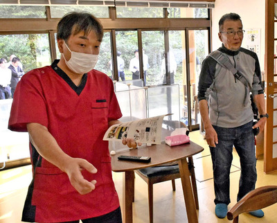 クマの侵入経路について説明を受ける溝口さん（右）