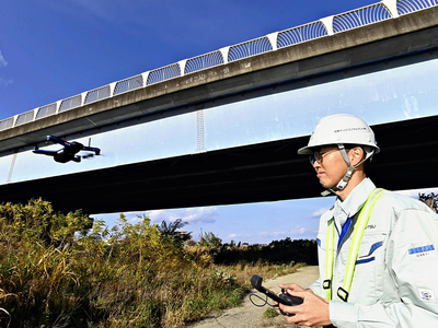 ドローンを使って橋梁の点検を行う社員