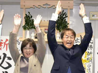 万歳三唱して初当選を喜ぶ小松氏。左は妻直美さん