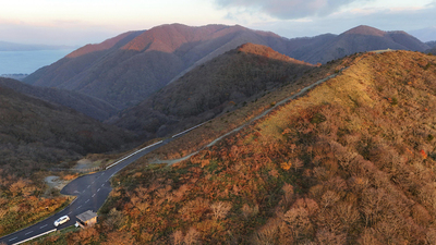 郡山市の逢瀬町と湖南町にまたがる御霊櫃峠。女性として初めてエベレスト登頂を成し遂げた登山家の故田部井淳子さんをモデルにした映画「てっぺんの向こうにあなたがいる」のロケ地の一つ。山頂付近から見下ろすと市内を一望できる。左上は猪苗代湖＝郡山市逢瀬町多田野（ドローン撮影）