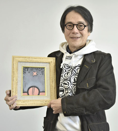 作品を手に来場を呼びかける国広さん